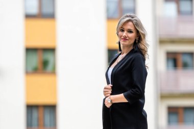 Bulanık şehir arka planına karşı genç, pozitif, zarif bir iş kadınının portresi.