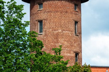 Mavi gökyüzüne karşı eski bir kırmızı tuğla su kulesinin yakın görüntüsü, pencereli orta bölüm
