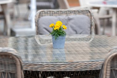 Restoranın dışındaki boş masa, kaldırımdaki kafe, saksıdaki çiçek buketi. 