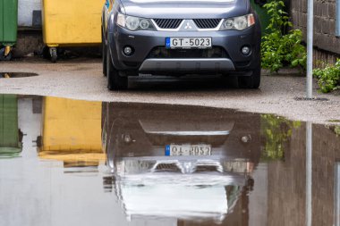 Riga, Letonya, 26 Mayıs 2021: Mitsubishi Yabancısı yağmur sonrası su birikintisinin ön yansıması, yakın çekim