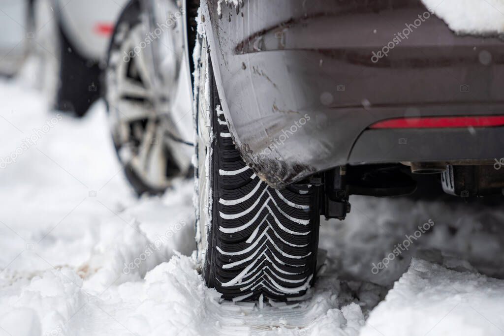 rear view of car with winter tyres in snowy road, close-up