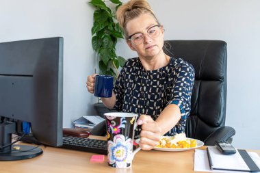 Çekici, orta yaşlı, gözlüklü bir kadın. Öğlen ofiste, masanın başında.