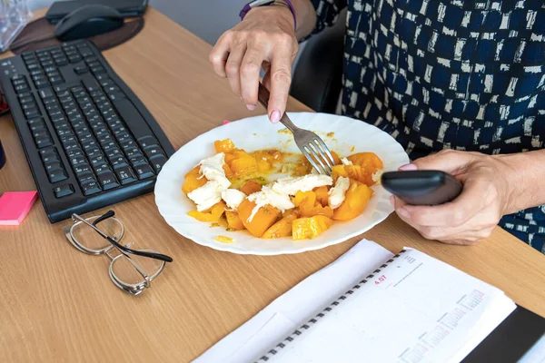 busy office woman eats lunch at her workplace without interrupting work, desk top view