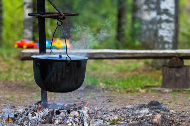 Ormandaki kamp ateşinde yemek pişirmek, yemek kampı konsepti kırsal kesimdeki evde şenlik ateşi yakmak.