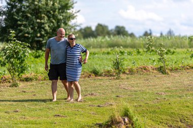 Romantik orta yaşlı çift bahçede yürüyor, mutlu bir ilişki konsepti.