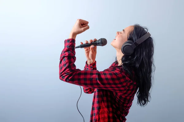 expressive female singing with a microphone and headphones, isolated on light background, mock up, copy space