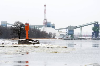 Soğuk ve sisli bir kış sabahı, Riga, Letonya 'da deniz feneri ve konteyner vinçleriyle liman manzarası