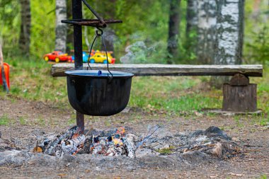 Ormandaki kamp ateşinde yemek pişirmek, yemek kampı konsepti kırsal kesimdeki evde şenlik ateşi yakmak.