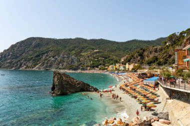 Monterosso kasabasındaki plajın kıyısında heybetli bir kaya. Birçok insan denizde yüzüyor.