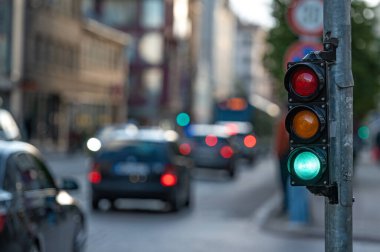 Trafik ışıklarıyla şehir trafiğini bulanık görmek, ön planda yeşil ışığı olan bir semafor.