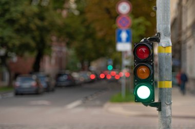 Trafik ışıklarıyla şehir trafiğini bulanık görmek, ön planda yeşil ışığı olan bir semafor.