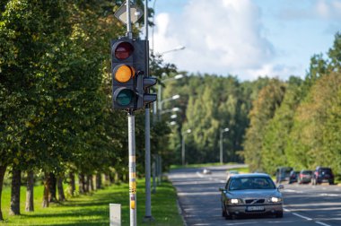 Riga, Letonya - 3 Eylül 2021: Odaklanamayan şehir caddesinde turuncu ışıklı trafik semaforuna yakın çekim 