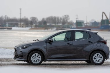 Riga, Letonya - 9 Şubat 2021: Metalik gri Toyota Yaris Hybrid Y20 versiyonu Hatchback arabası deniz kenarına park edilmiş.