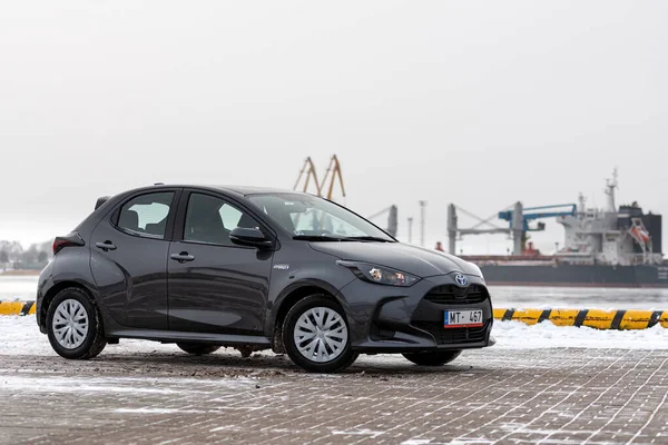 Riga, Letonya - 9 Şubat 2021: Metalik gri Toyota Yaris Hybrid Y20 versiyonu Hatchback arabası deniz kenarına park edilmiş.