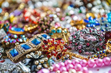 Çeşitli renkli parlak mücevherler ve kostüm mücevherlerinin soyut arkaplanı, yumuşak, seçici odaklanma