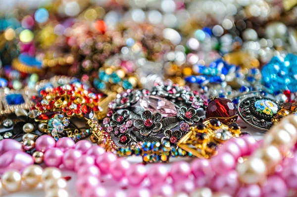 Çeşitli renkli parlak mücevherler ve kostüm mücevherlerinin soyut arkaplanı, yumuşak, seçici odaklanma