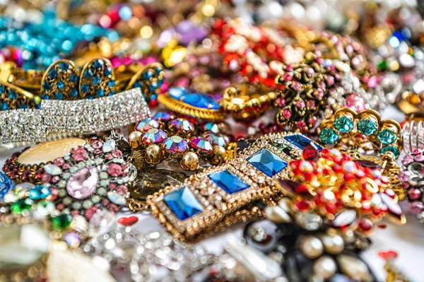 Çeşitli renkli parlak mücevherler ve kostüm mücevherlerinin soyut arkaplanı, yumuşak, seçici odaklanma