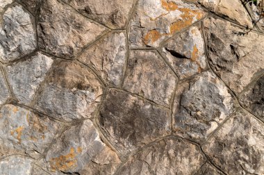 Eşsiz altıgen şekil ve renklere sahip desenli taş bir duvarın yakın görüntüsü.