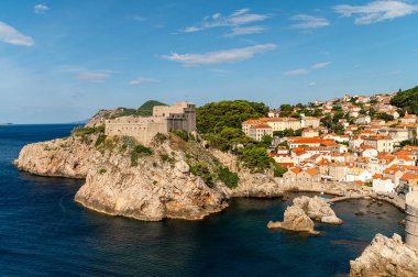 Dubrovnik, Hırvatistan - 17 Eylül 2025: Ziyaretçiler açık gökyüzü altındaki Dubrovnik kıyı şeridi ve antik kalenin manzarasının keyfini çıkarıyorlar.