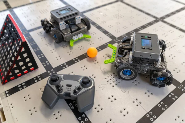 İki robot masadaki bir ızgarada geziniyor ve yakınlardaki bir kontrolörle eğlenceli bir aktiviteye girişiyor..