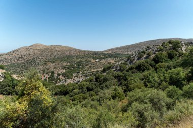 Bereketli yeşil ve engebeli tepeler Girit 'in açık mavi gökyüzünün altındaki doğal güzelliğini gözler önüne seriyor..