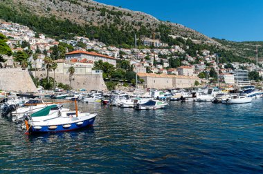 Dubrovnik, Hırvatistan - 21 Eylül 2025: Dubrovnik 'teki büyüleyici tepeleri ve büyüleyici binaları olan tekneler sakin bir marinada dinleniyor.