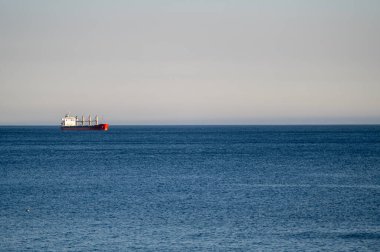 Kargo gemisi gün boyunca berrak bir gökyüzünün altında sakin bir okyanusta yol alıyor.