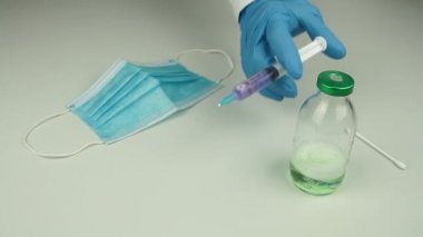 Mavi eldivenli doktorun elleri covid 19 aşısını incelemek için tıbbi örnek.