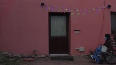 Tekerlekli sandalyedeki yaşlılar, sağlık maskesi ve noel ışıkları.