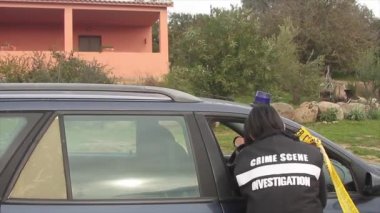Olay yeri inceleme dedektifi elinde bir masa ile olay yerini inceliyor.