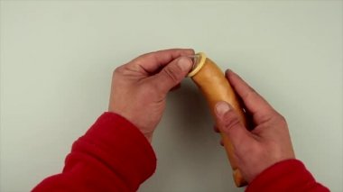Cinsel eğitimin temsilcisi olarak sosise prezervatif takan adamın elleri.