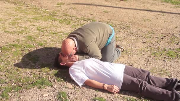 Homem praticando ressuscitação para uma mulher com massagem cardíaca e boca a boca — Vídeo de Stock