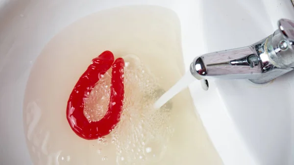 Jouets sexuels féminins tels que les vibrateurs roses qui sont lavés sous l'eau de l'évier Photos De Stock Libres De Droits
