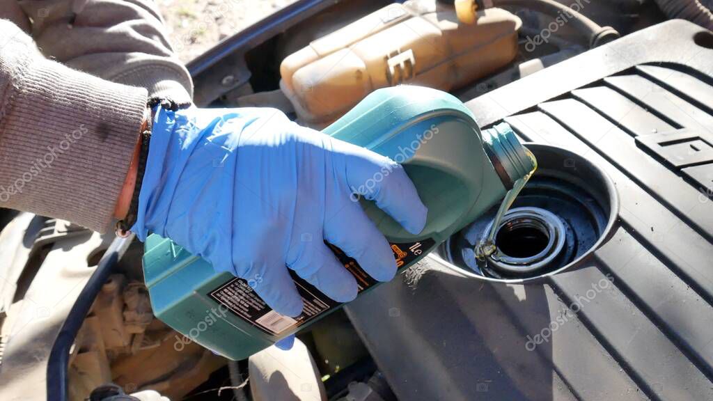 hand of a mechanic with blue glove making the engine oil change