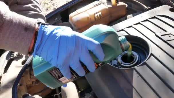 Рука механика с голубой перчаткой, меняющего машинное масло — стоковое видео