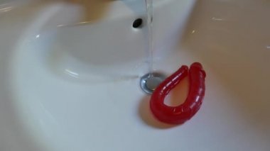 Lavabo suyunun altında yıkanan pembe vibratörler gibi dişi seks oyuncakları.