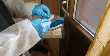 Olay yerindeki olay yeri inceleme dedektifi mavi fenerlerle inceleme yapıyor ve bir cinayetin işlendiği evin kapı kolundan alınan laboratuvara bilimsel kanıtlar götürüyor.