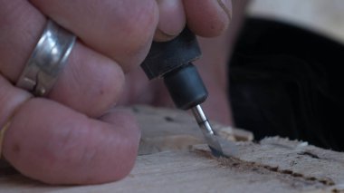 Aletlerin aşırı ısınmasından dolayı ahşabı dumanla kesen aletlerle işçi elinin yakın plan görüntüsü.