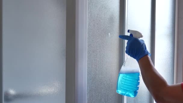 Mujer desinfectante ventanas de la caja de ducha con spray bactericida azul contra virus — Vídeo de stock