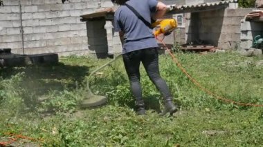 Elektrikli çim biçme makinesiyle çimleri 50 fp hızla biçen beyaz bir kız.
