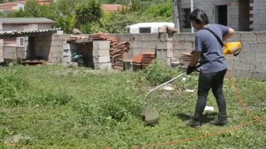 Elektrikli çim biçme makinesiyle çimleri 50 fp hızla biçen beyaz bir kız.
