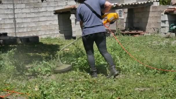 Kaukázusi lány, aki elektromos fűnyíróval 50fps-en nyírja a füvet. — Stock videók