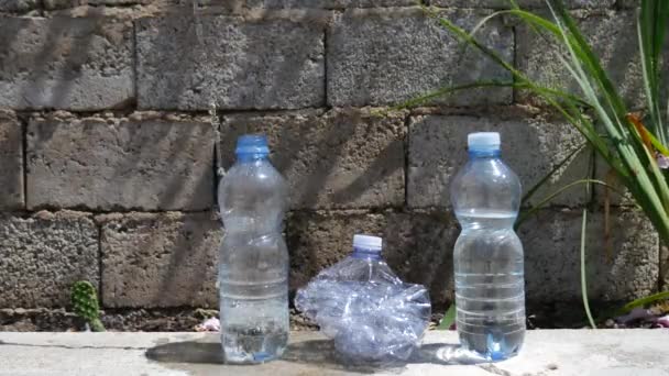 Tres botellas de agua, una de las cuales está arrugada. uno está lleno de agua — Vídeo de stock