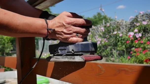Hand van timmerman met behulp van elektrische schuurmachine met schuurpapier schuren een leuning — Stockvideo