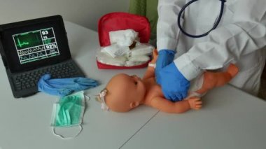 Doktor, yeni doğan bebeğe kalp masajı yapmayı öğretiyor.