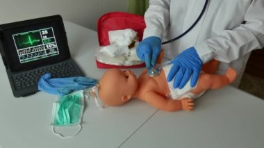Doktor, yeni doğan bebeğe kalp masajı yapmayı öğretiyor.