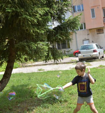 Parkta baloncuklarla oynayan çocuk