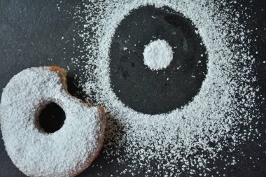 Siyah arkaplanda çörek ve pudra şekeri.,