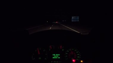Parlak gösterge paneli ve yol ışıklarıyla otoyolda gece araba sürüşü.