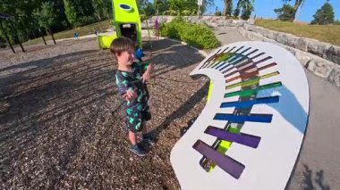 Çocuk oyun parkında büyük, renkli bir ksilofonla oynuyor.